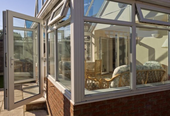 A conservatory with it's doors open and the sun shining on it