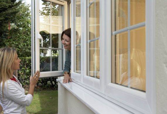 Woman leaning out of window talking to a woman