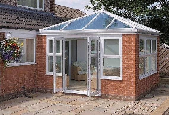 A conservatory with white frames attached to a modern home