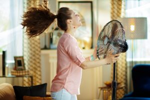 Woman blowing a large fan directly into face