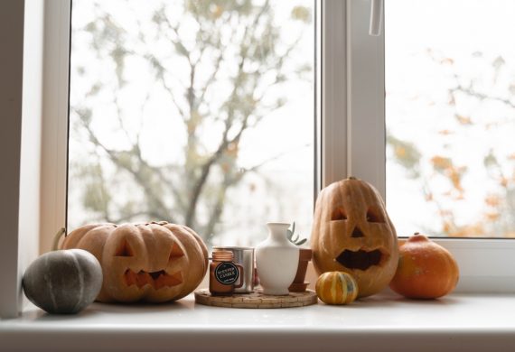 Pumpkins with faces cut out of them on a window sill