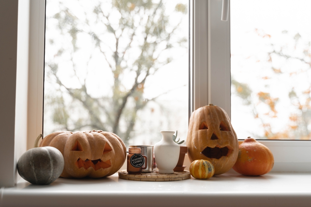 Pumpkins with faces cut out of them on a window sill