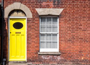 front of house with composite bright yellow doors with window next to it