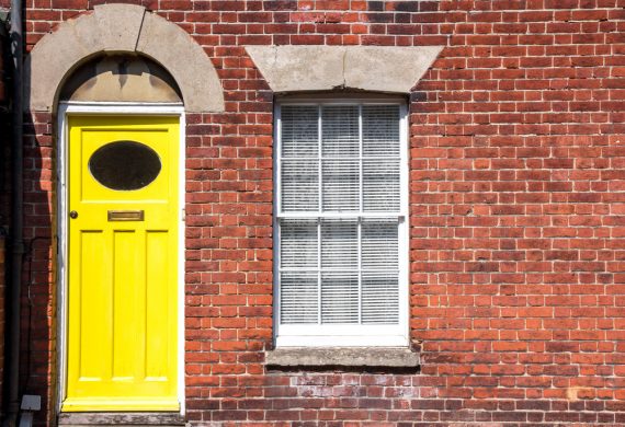 front of house with composite bright yellow doors with window next to it