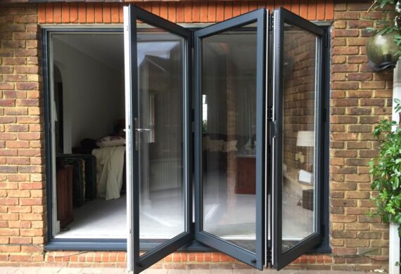 Aluminium bi‑folding doors with slim modern frames fully opening to create an indoor–outdoor living space.
